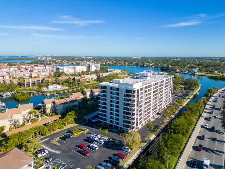 Aerial view of a Florida condominium community with a mid-rise building, townhomes, and canals