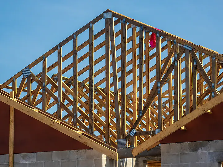 Wood roof trusses of a Florida home under construction against a blue sky