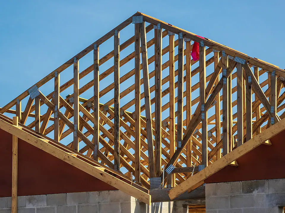 Wood roof trusses of a Florida home under construction against a blue sky
