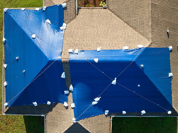 Aerial view of Florida homes with blue tarps over storm-damaged roofs